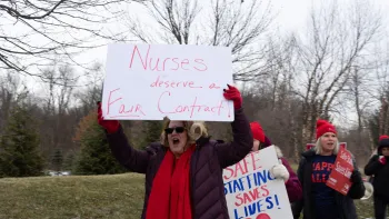 A nurse holding a sign that says "Nurses deserve a fair contract"